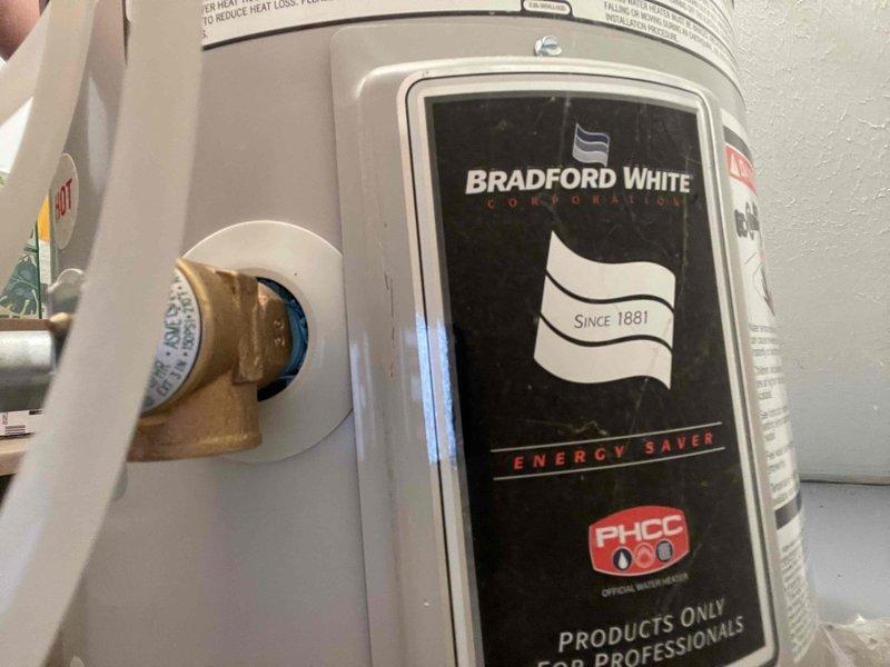 Responded to a no hot water and low water pressure complaint at a downstairs office location. Upon inspection, found a Bradford White Energy Saver tanked water heater with associated pressure components and plumbing connections. Evaluated the water heater system, pressure relief valve, expansion tank, and connected supply lines with brass fittings to diagnose the reported issues and restore proper hot water delivery and water pressure to the facility.