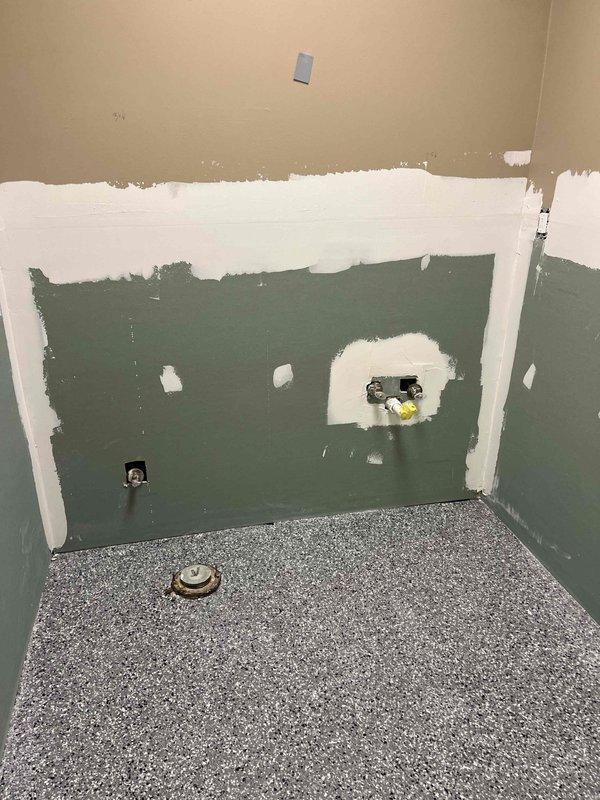 Conducted estimate for replacement of two bathroom faucets, two toilets, and one kitchen faucet in an unoccupied office space under renovation. Observed walls in various stages of preparation with plumbing rough-ins visible, including drain fittings and water supply pipes. Noted existing Rheem water heater with copper supply lines that will need to be connected to new fixtures once installed.