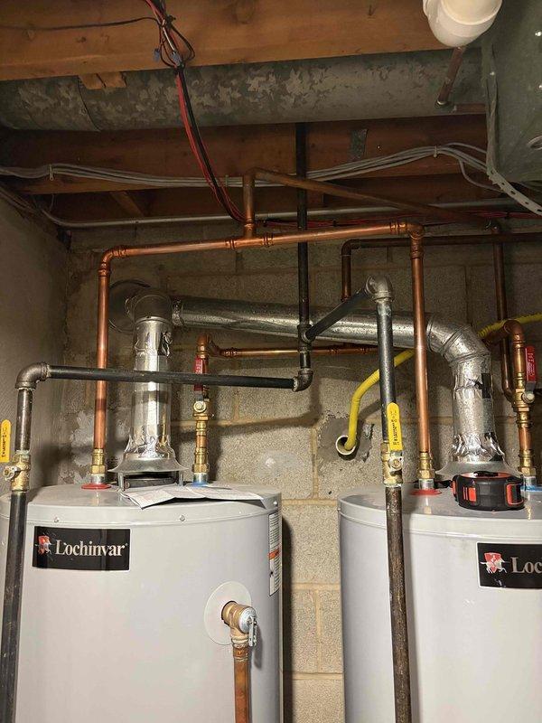 Completed comprehensive gas line inspection for new project with unknown system age. Inspected black iron gas piping in attic space with red-handled ball valve, verified connections and fittings, and examined dual Lochinvar water heater installation in basement with yellow flexible gas lines, multiple shut-off valves, and proper sediment traps. All gas line components, connections, and safety devices documented via photographs for project planning purposes.